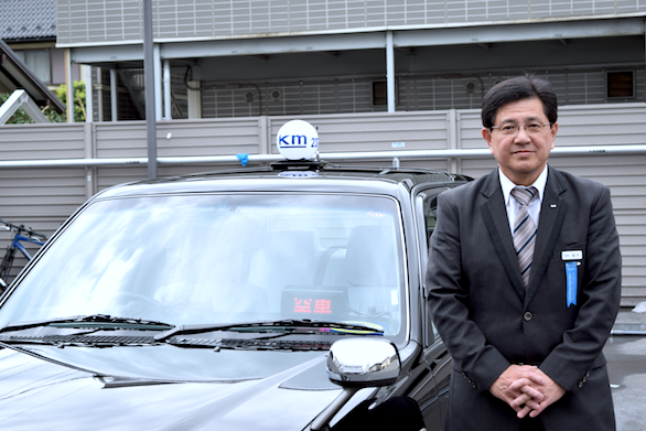 タクシーの横に立つ、国際自動車（㎞タクシー）吉祥寺営業所所属のベテランタクシードライバー橋本さんの写真