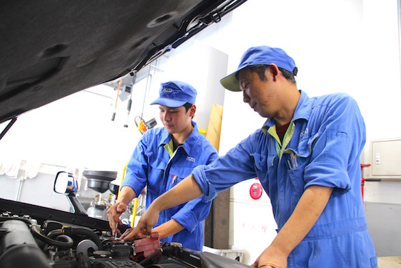 同僚と一緒に整備をしている国際自動車（㎞タクシー）板橋整備工場で働く新卒整備士小林さんの写真