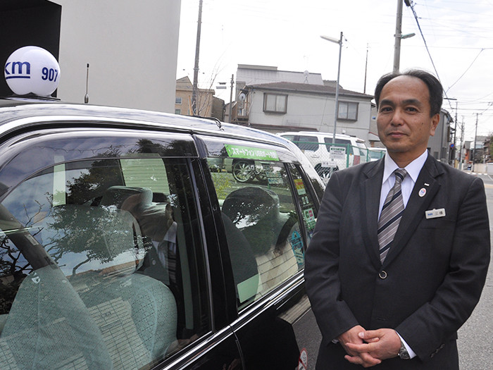 タクシーの横に立つ国際自動車（㎞タクシー）の稼げるタクシードライバー三橋さんの写真