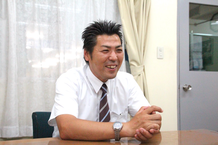 笑顔で話をしているケイエム観光バス株式会社のバスドライバー阿部さんの写真