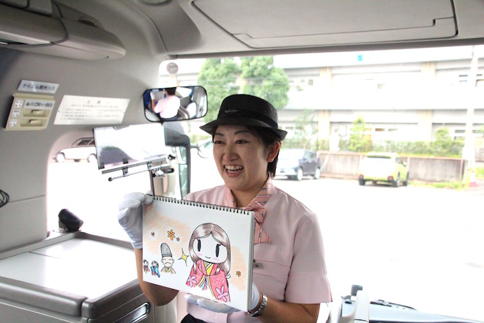 紙芝居を笑顔で読んでいる、ケイエム観光バス株式会社東京営業所で観光バスガイドを務める、通訳案内士の資格を持つ通訳ガイド森さんの写真